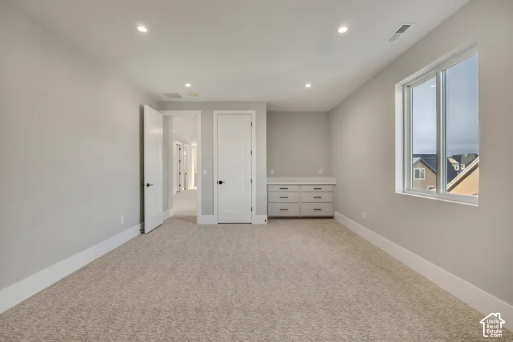 Recessed lighting illuminates this room featuring carpet flooring and a built-in cabinet with six drawers and a light-toned countertop