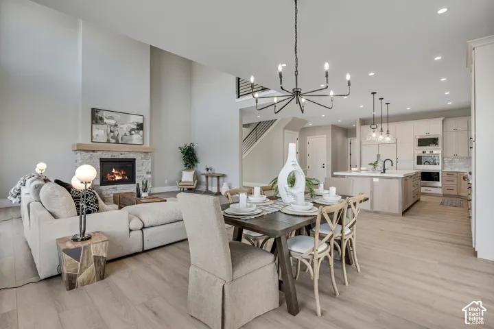 Vaulted ceiling, stone surround fireplace with wood mantel, wood-finish flooring, built-in kitchen appliances, and kitchen island with pendant lighting