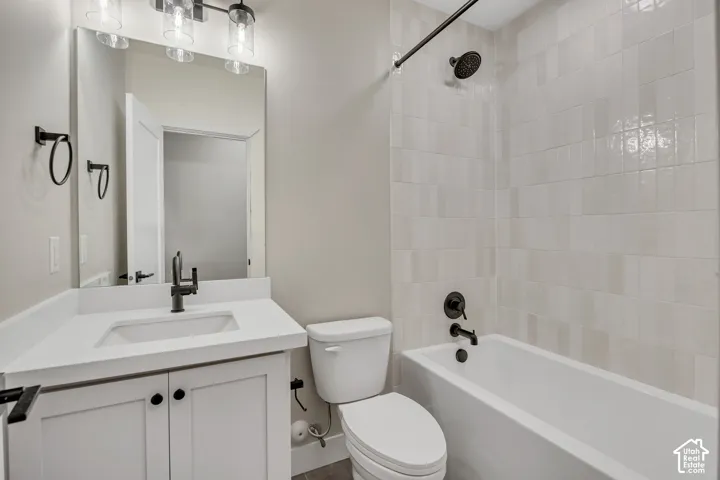 Bathroom featuring a white vanity with integrated sink, matte black fixtures, an overhead light bar, and a tiled shower-tub combination