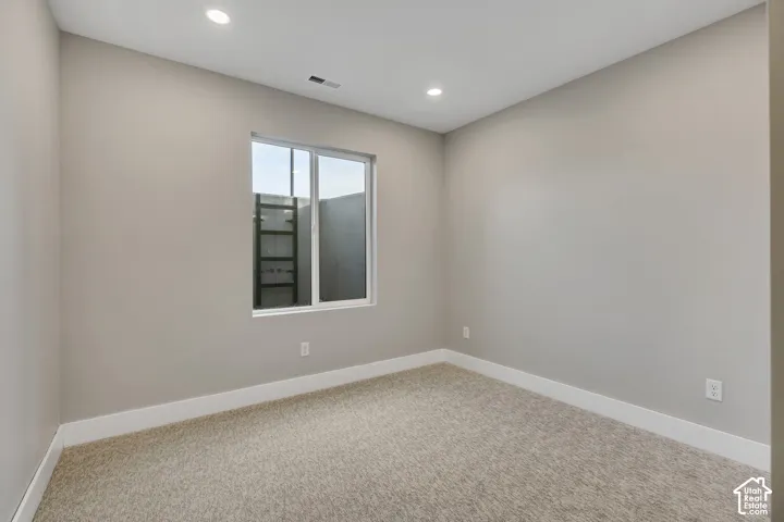 Neutral wall paint, recessed lighting, white window trim, and carpet flooring
