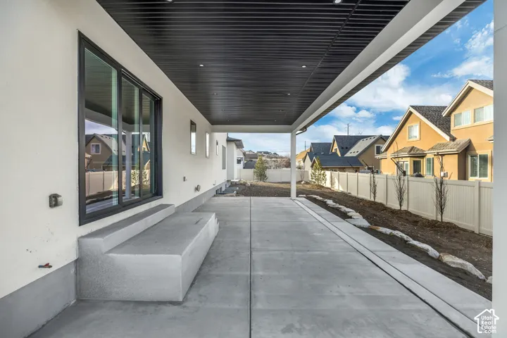 Expansive covered patio with a black slatted ceiling, recessed lighting, and a concrete slab