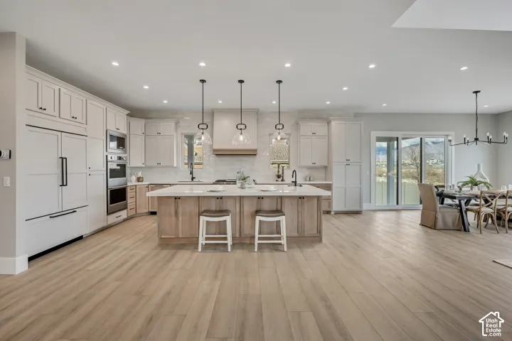Gourmet kitchen with wood-finish flooring, two-tone cabinetry, a large center island, and stainless steel appliances