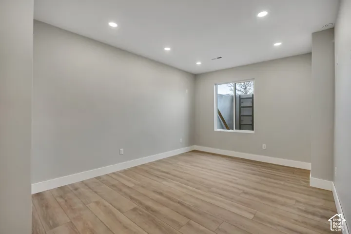 Recessed lighting, wood-finish flooring, white trim, and a window with a white frame