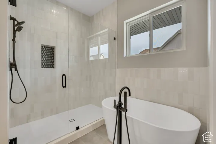 Walk-in shower with a glass enclosure, black hex-tile shower niche, and matte black fixtures