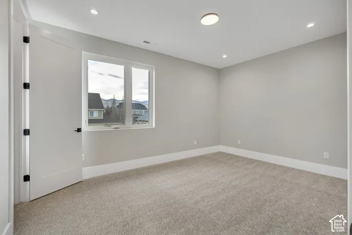Neutral tone paint, recessed lighting, white trim, carpet flooring, and a large window