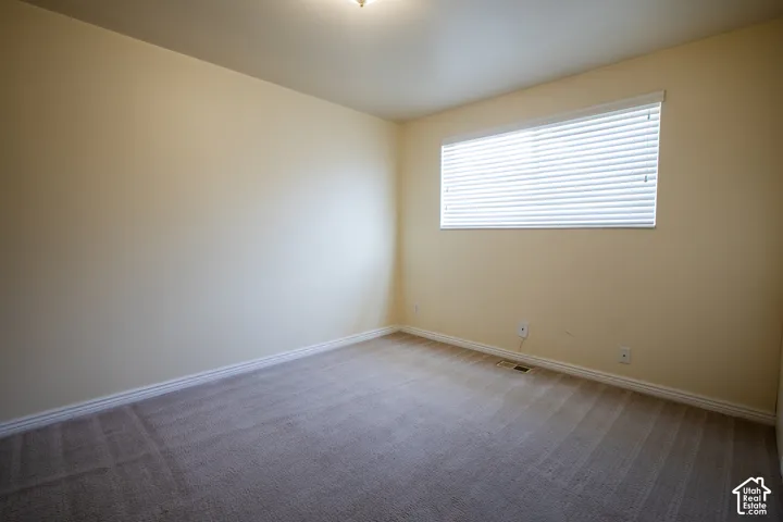 Carpeted room featuring a single window with horizontal blinds and a ceiling-mounted light fixture
