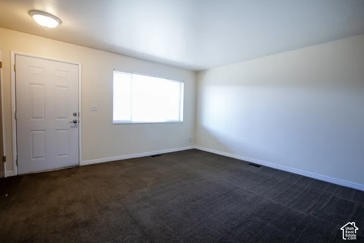 Neutral wall paint, textured carpet flooring, white window blinds, and an overhead flush mount light fixture