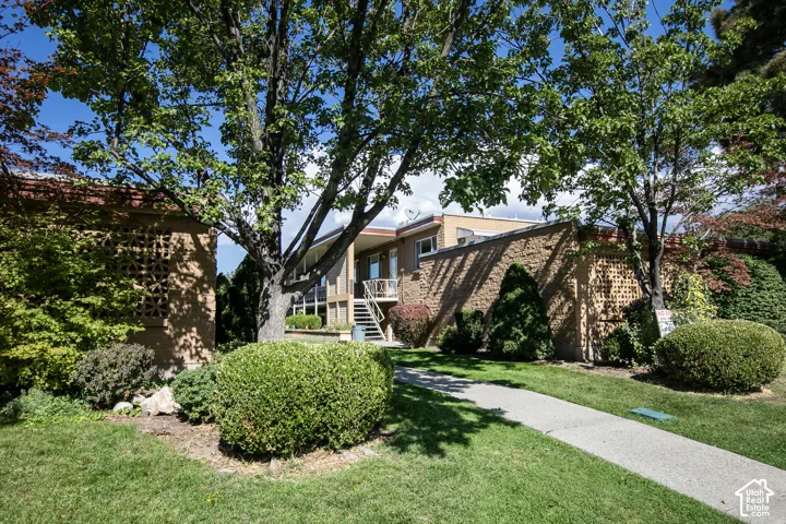 Manicured lawn, mature trees, concrete walkway, brick exterior, and decorative lattice screen