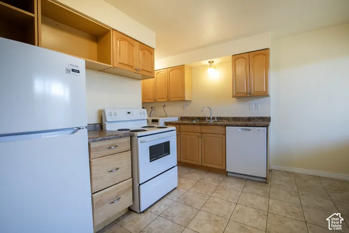 Kitchen featuring light wood-finish cabinetry, a ceramic tile floor, and a double-basin stainless steel sink