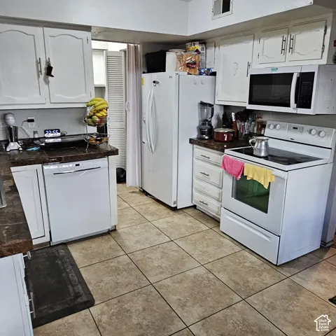 Kitchen featuring white cabinetry, tile countertops, a white dishwasher, a white electric range, and a white refrigerator