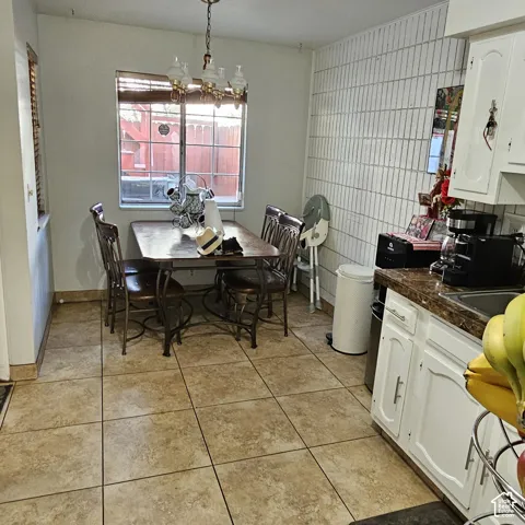 Tile flooring with a matte finish, white lower cabinetry, and a countertop with an integrated sink