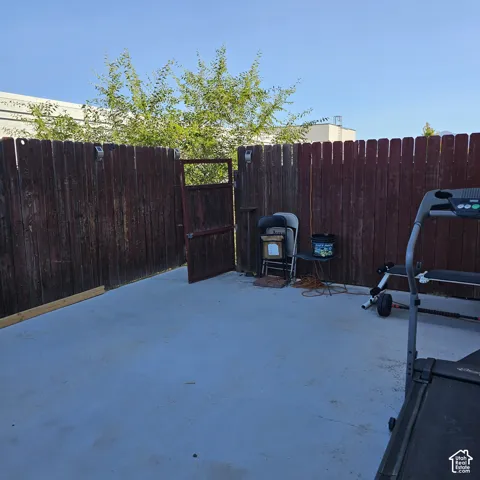 Concrete patio space featuring a wood fence perimeter and a gate