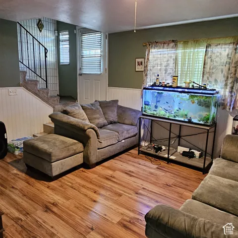 Wood-finish flooring throughout, complemented by wainscoting and a staircase with an iron railing