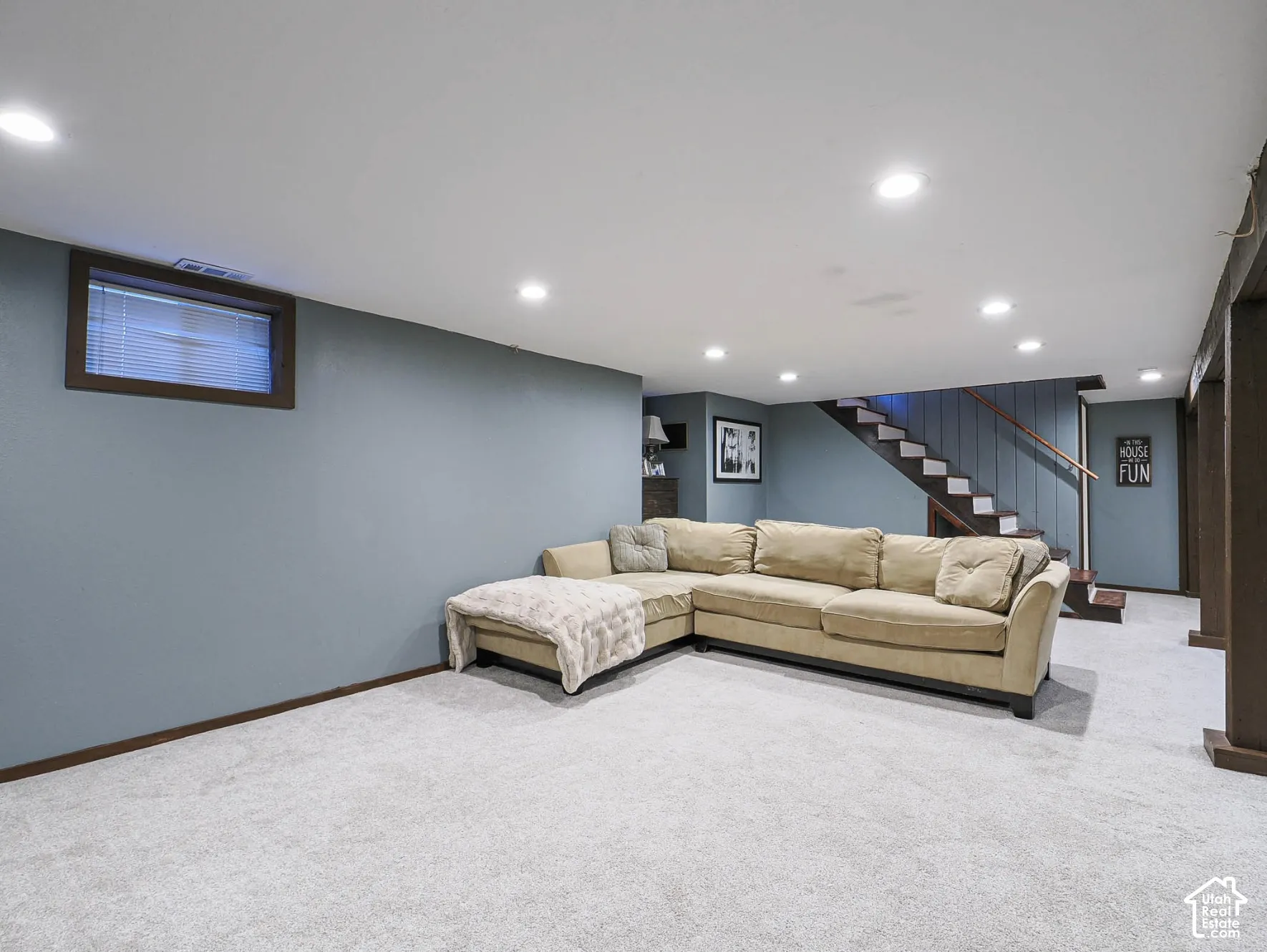 Recessed lighting, light gray carpeting, window with blinds, painted walls, and staircase with wood handrail