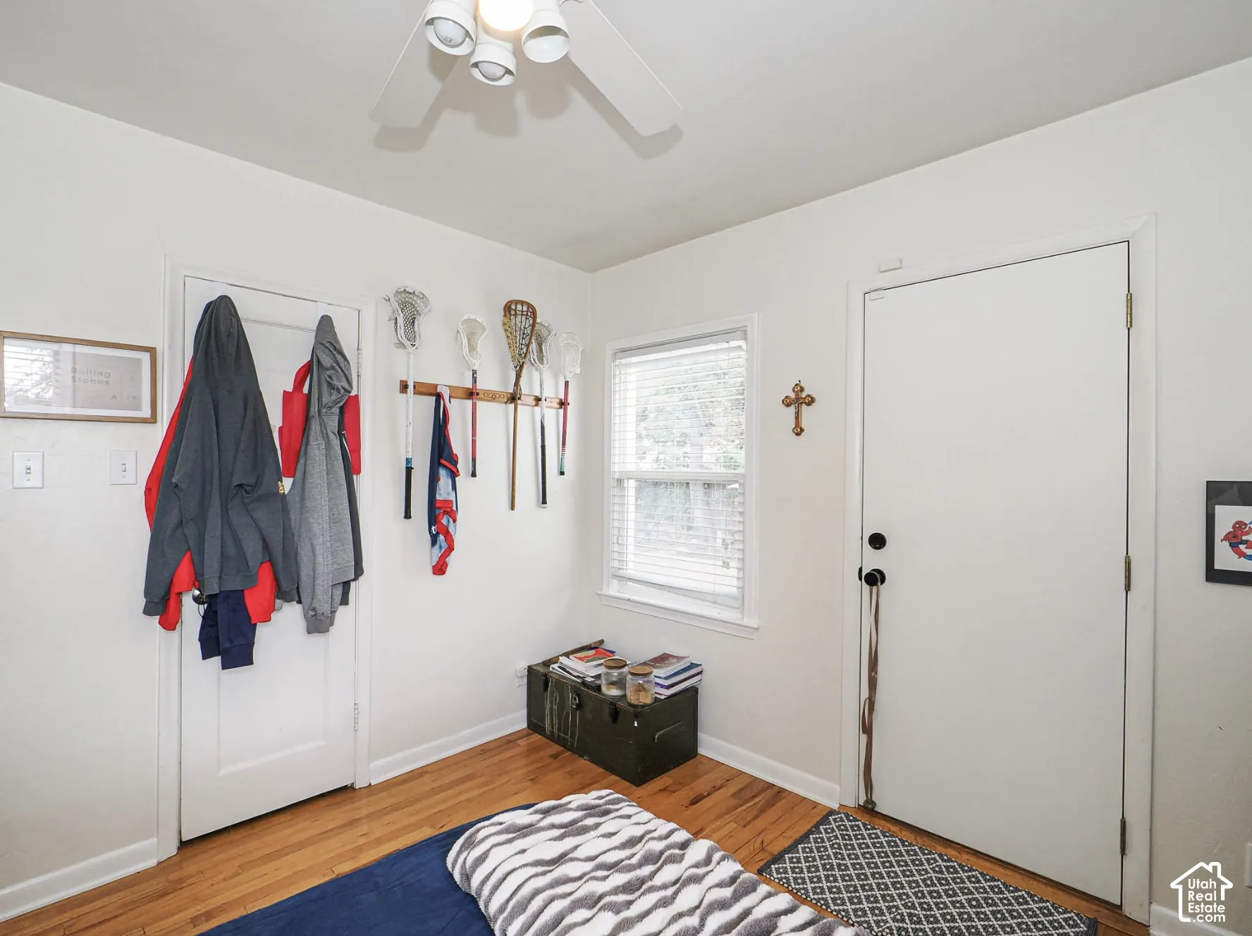 Hardwood flooring, ceiling fan, white paneled door, window with blinds, white wall finish