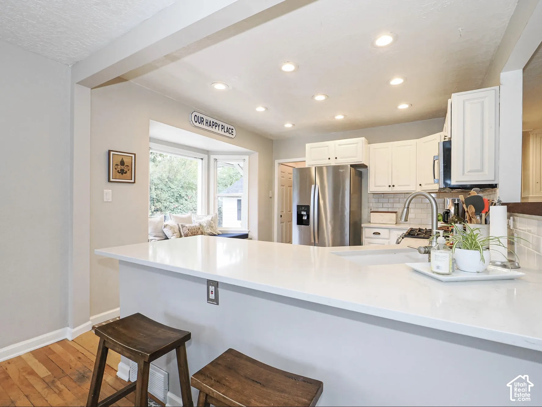 Kitchen featuring white cabinetry, stainless steel refrigerator, white subway tile backsplash, white countertops, and recessed lighting