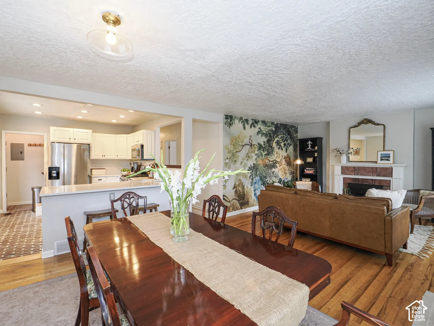 Open-concept layout with wood-finish flooring, white cabinetry, and stainless steel appliances