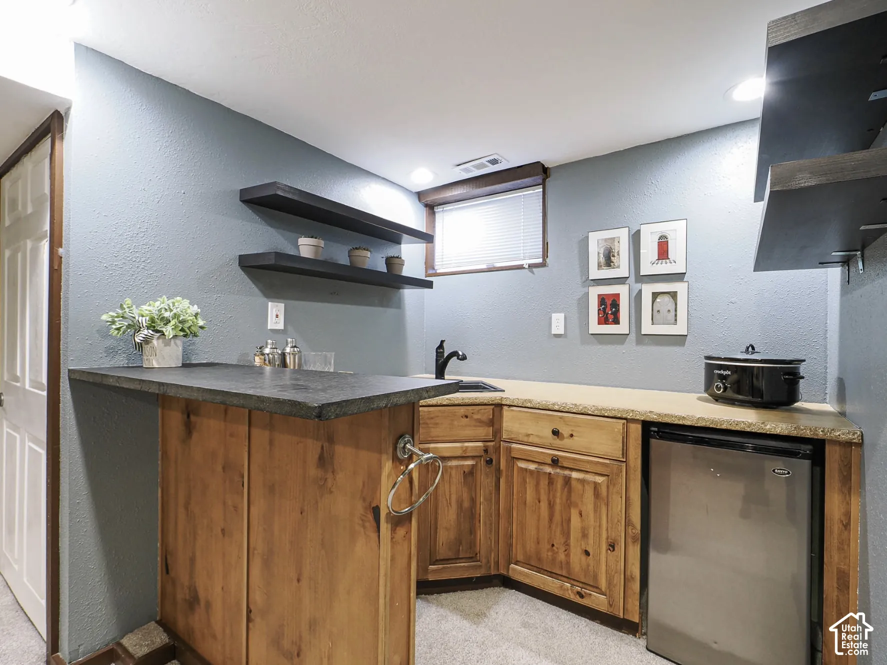 Wet bar with rustic wood cabinetry, dark countertops, and a built-in compact refrigerator