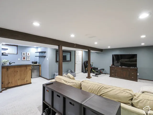 Recessed lighting throughout, exposed wood-finish beams, integrated wet bar with sink, mini-refrigerator, and wall-mounted shelving