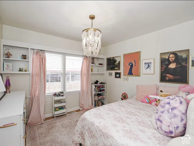 Built-in shelving flanking a window with blinds, overhead chandelier with beaded detail, and wood-finish flooring
