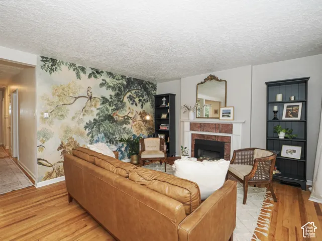 Hardwood flooring, decorative wall mural, brick-surround fireplace, white mantel, and built-in shelving