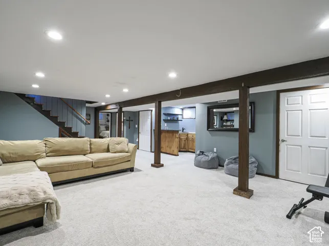 Recessed lighting, wood-finish support beams, wood-finish wet bar, paneled interior doors, and carpet flooring