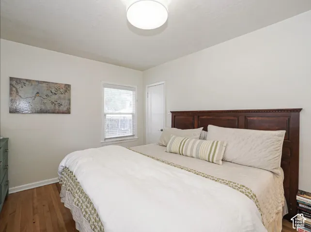 Hardwood flooring, single window with blinds, and white walls
