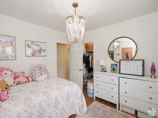 Beaded chandelier, wood-finish flooring, white walls, and a built-in closet with shelving