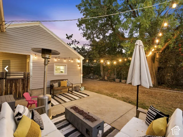 Concrete patio with string lights, a built-in fire pit, and an adjacent siding exterior