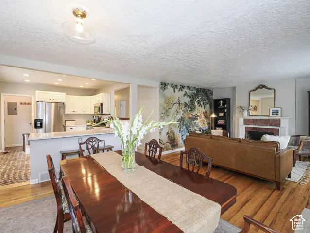 Open-concept layout with wood-finish flooring, white cabinetry, and stainless steel appliances