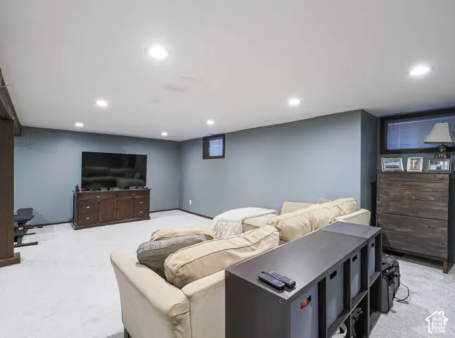 Recessed ceiling lighting, light-toned carpeting, wood-finish support columns, a built-in media console, and a built-in storage unit