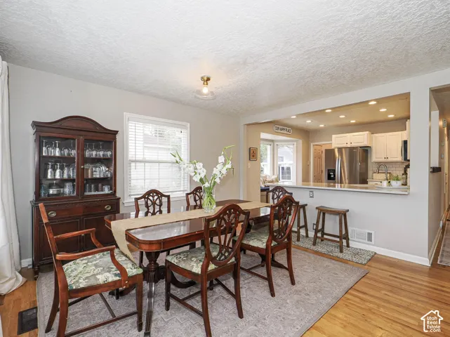 Hardwood flooring throughout, with a pass-through opening to the kitchen featuring white cabinetry and stainless steel appliances