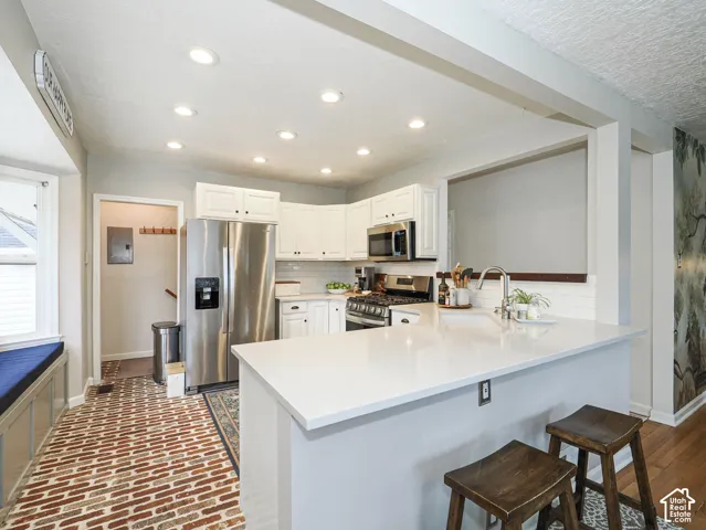 Kitchen with stainless steel appliances, white cabinetry, recessed lighting, and a center island with a light-toned countertop