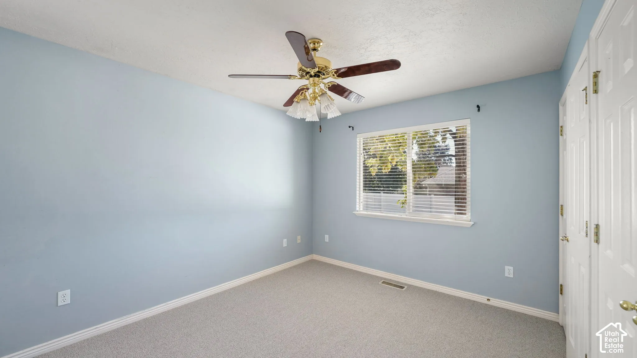 Primary bedroom featuring carpeted flooring, ceiling fan with integrated lighting, window with horizontal blinds, and white paneled doors
