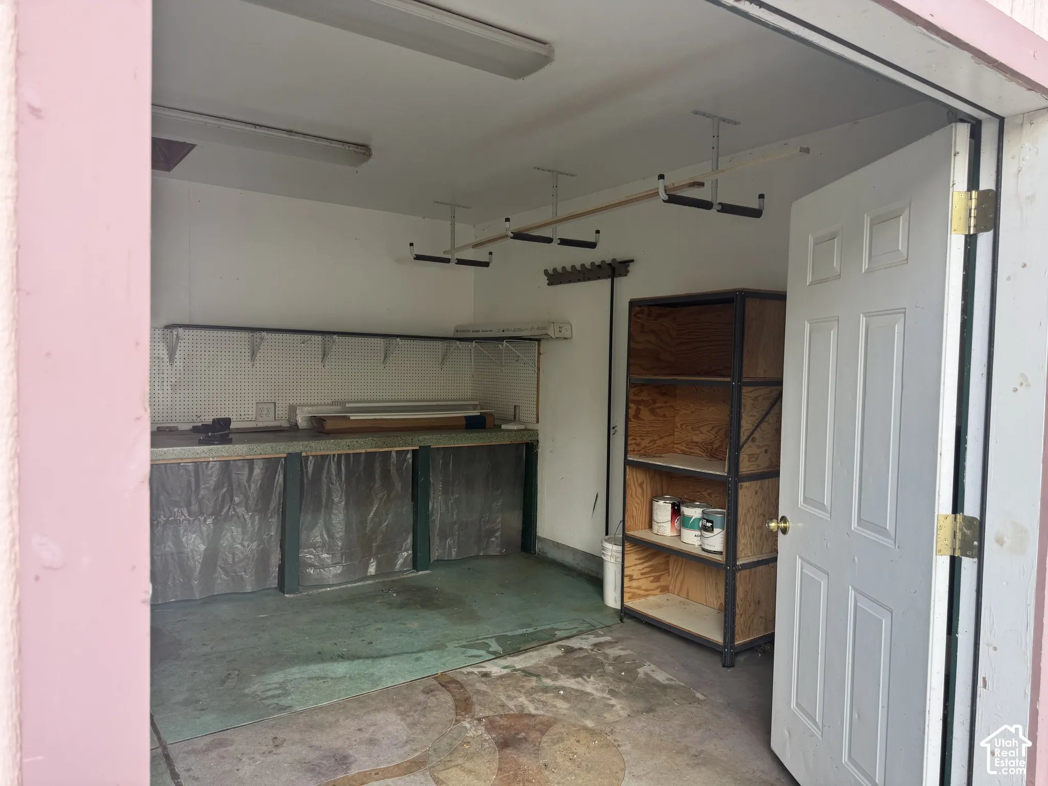 Shop workspace with built-in shelving, pegboard wall, and fluorescent lighting