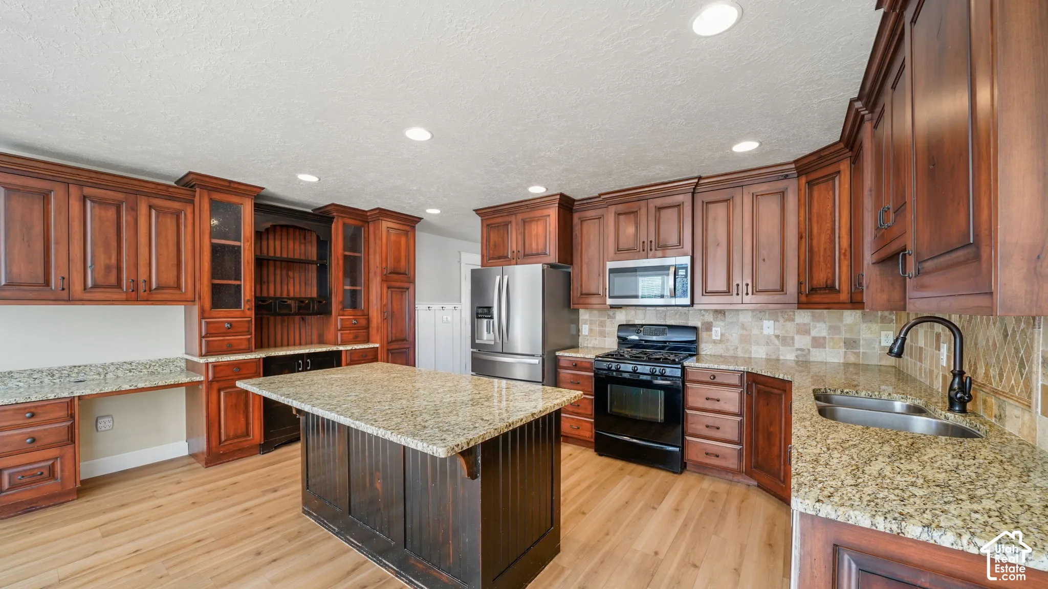 Expansive kitchen featuring wood-finish flooring, recessed lighting, wood cabinetry, granite countertops, and stainless steel appliances