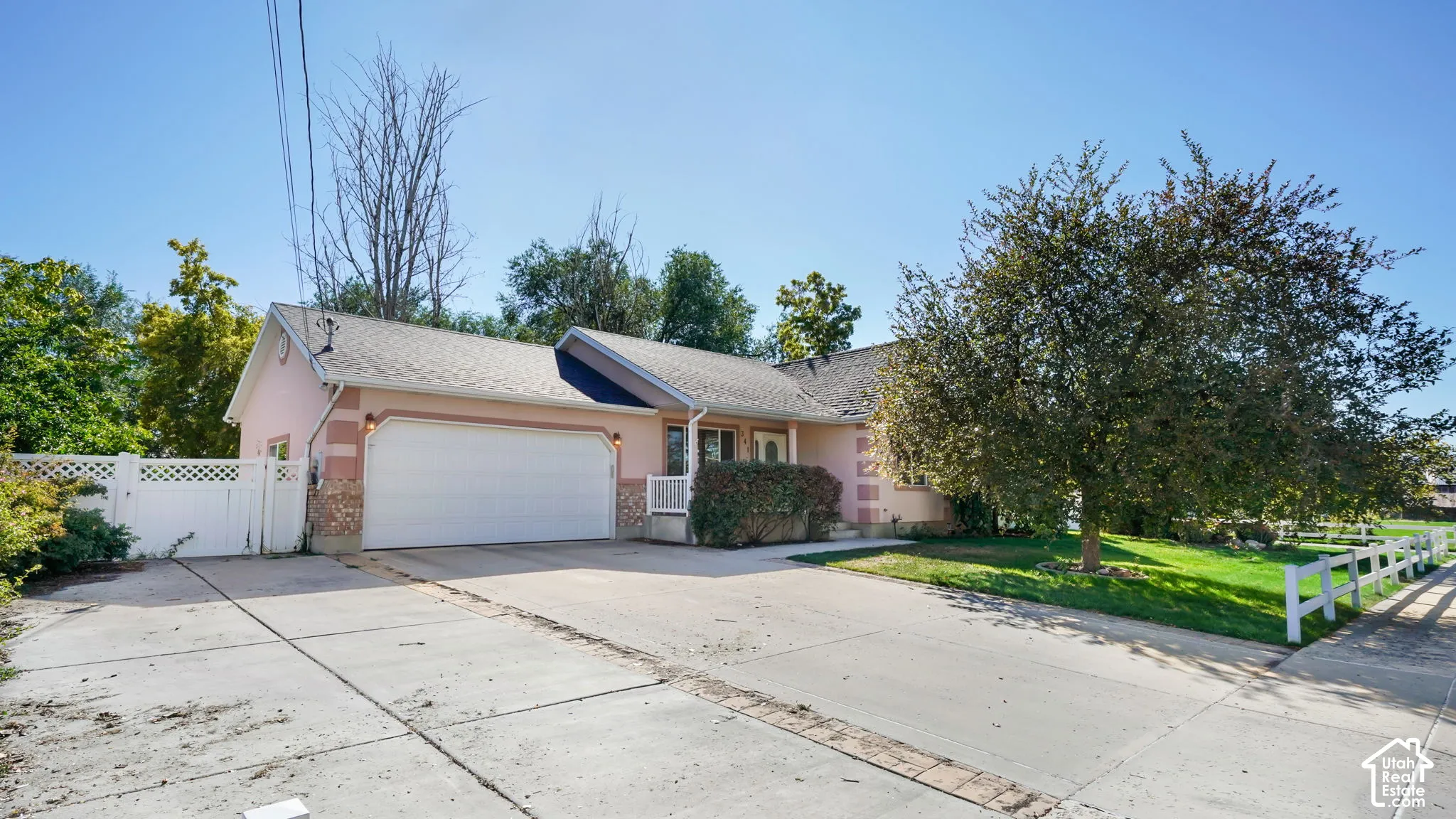 Two-car garage with concrete driveway and mature trees and fence.