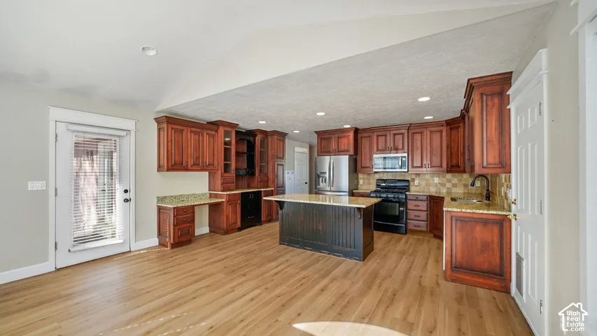 Kitchen featuring wood-finish flooring, dark wood cabinetry, a central island, and stainless steel appliances