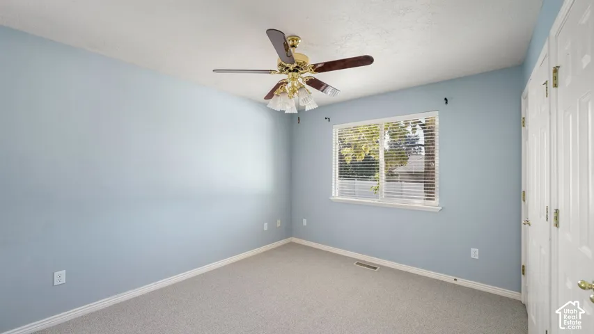 Primary bedroom featuring carpeted flooring, ceiling fan with integrated lighting, window with horizontal blinds, and white paneled doors