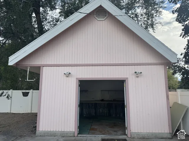 Gable roof structure with a prominent roofline, vertical panel siding, and a double open entryway