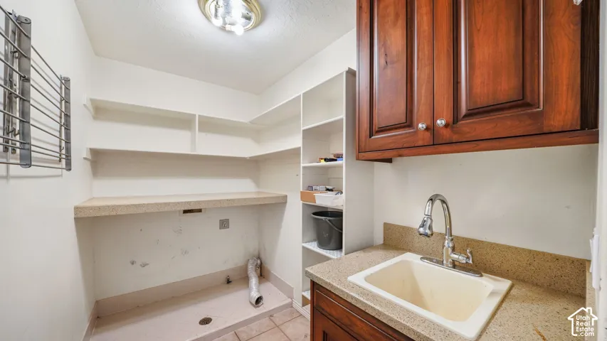 Utility room with built-in shelving, a utility sink, and wood-finish cabinetry