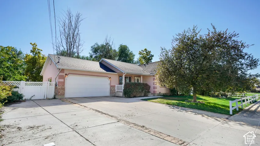 Two-car garage with concrete driveway and mature trees and fence.