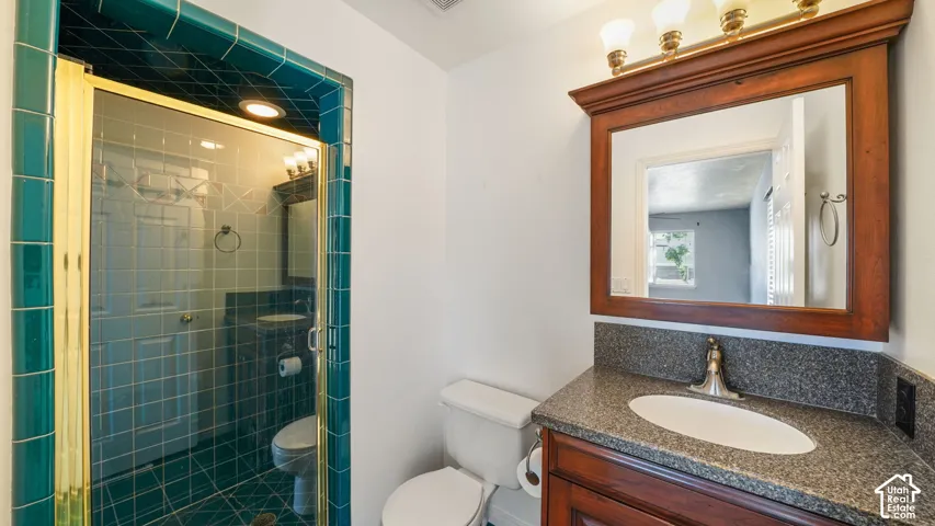 Primary bathroom featuring a wood-finish vanity with an integrated sink, a dark speckled countertop, and a framed mirror with an overhead light fixture