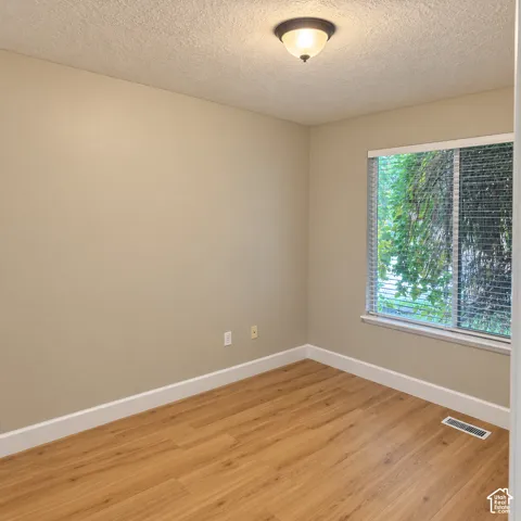 Wood-finish flooring, neutral wall tones, white trim, and a window with blinds