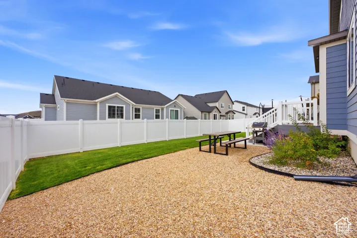 Expansive gravel yard with a dedicated lawn area, white privacy fencing, and a multi-level deck structure