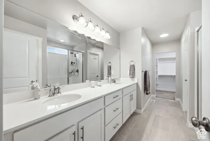 Double vanity with white cabinetry, integrated sinks, chrome fixtures, and a broad mirror