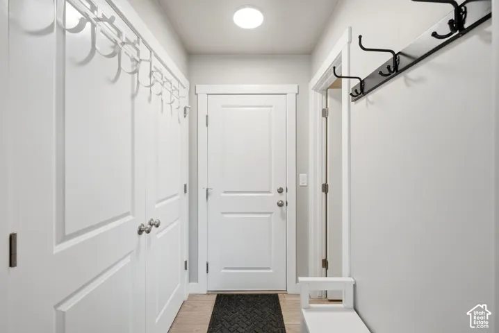 White shaker-style doors, durable wood-finish flooring, recessed ceiling lighting, and a built-in coat rack