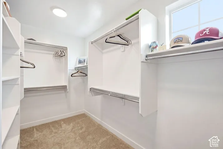 Walk-in closet featuring white built-in shelving, chrome hanging rods, and a window for natural light