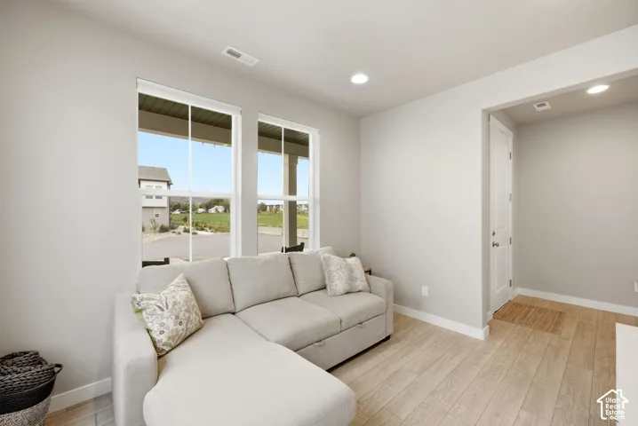 Recessed lighting, light-toned wood-finish flooring, and white trim