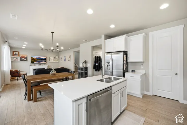 Open-concept layout featuring wood-finish flooring, recessed lighting, and a kitchen island with an integrated stainless steel sink and dishwasher